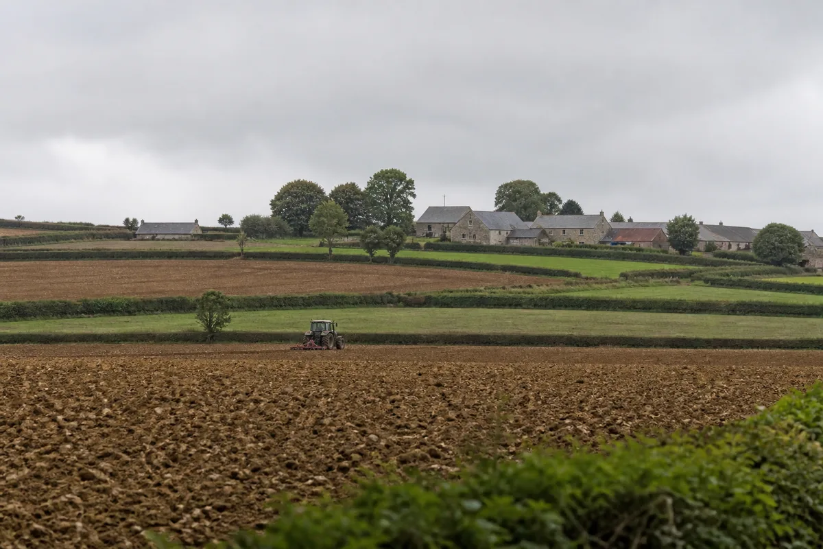 Tracteur équipé de pneus à crampons traversant une parcelle labourée en Normandie